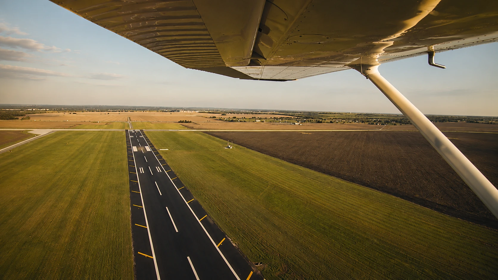 Runway approach viewed beneath an aircraft wing
